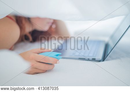 A Woman Lies In Bed Holding A Clitoral Vibrator And Watching Porn On A Laptop. The Girl Has Sex Onli