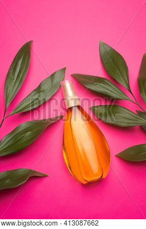 Suntan Oil On A Pink Background . Suntan Oil And Green Leaves. Vacation. Protect Your Skin From The 