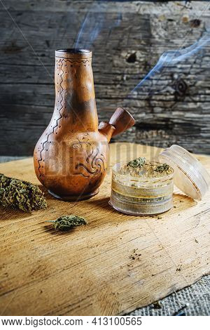 Old Brown Steamung Bong And Open Cannabis Grinder With Chopped Marijuana Weed And Medical Cannabis I