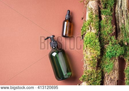 Unlabelled Cosmetic Bottle On Brown Background, Natural Moss Over Branches, Bark. Skin Care, Organic
