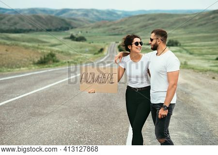 A Man And A Woman Are Hitchhiking. A Young Couple Goes Hitchhiking Around The Country. Free Hitchhik