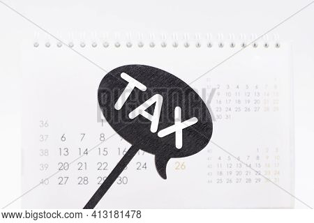 The Words Tax On The Black Poster In Front Of The Calendar. Business , Tax Concept.