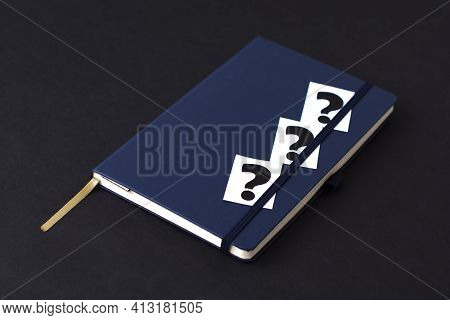 Blue Diary And Question Mark On A Black Background. Planning. Business Concept
