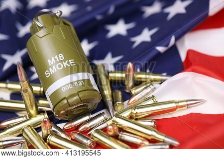 M18 Smoke Grenade And Many Yellow Bullets And Cartridges On United States Flag. Concept Of Gun Traff