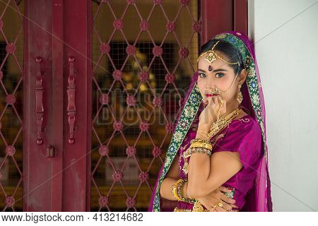 Portrait Asian Woman In A Margenta Indian Tradition Sari, She Is Looking At A Camera Touching Her Ch