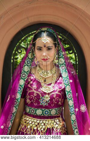 Portrait Asian Woman In A Margenta Indian Tradition Sari, She Is Looking At A Camera With Orange Wal