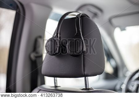 On-ear Headphones Hang On The Headrest In The Car. Technology Personal Multimedia System In A Modern