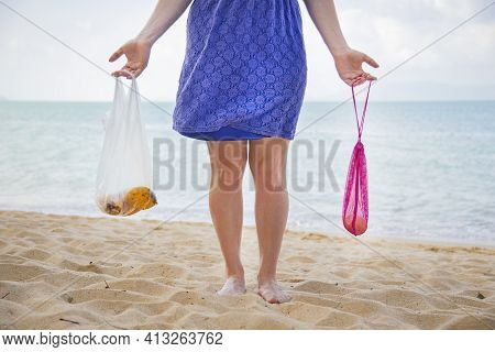 Woman Oo Beach Holds A Plastic Bag And A Mesh Shopping Bag. The Concept Of A Conscious Attitude To T