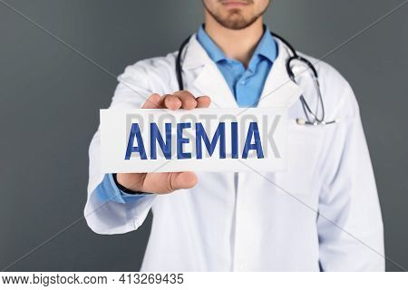 Doctor Holding Sign With Word Anemia On Grey Background, Closeup