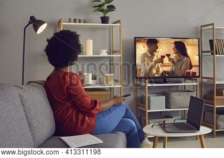 Young Woman Sitting On Couch At Home And Watching Romantic Soap Opera On Television