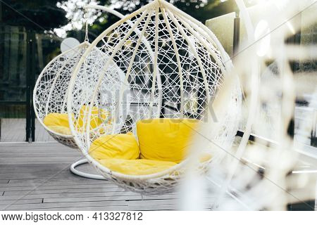 Hanging Wicker Chair With Yellow Cushions In Minimalistic Style Outdoor Interior. Demonstrating Tren
