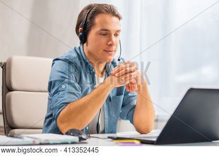 Workplace of freelance worker or sudent at home office. Young man works using computer and other devices. Remote job.