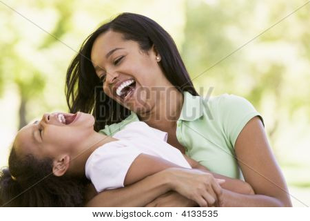Woman And Young Girl Outdoors Embracing And Laughing