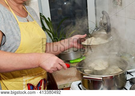 A Woman Takes Out Cooked Dumplings From A Pan Into A Transparent Plate