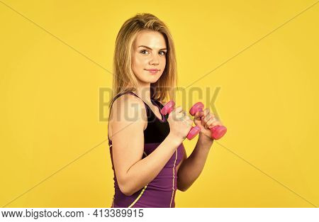 Muscular Woman In Training Pumping Up Muscles Of Hands. Girl Use Barbell Yellow Background. Slim Gir
