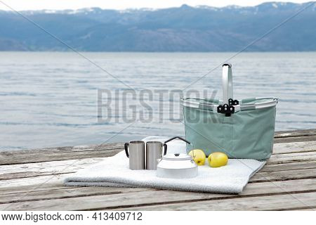 Picnic Basket With Apples, Thermoses And Cups With Blanket On The Wooden Bier. Hiking Outdoors. Picn