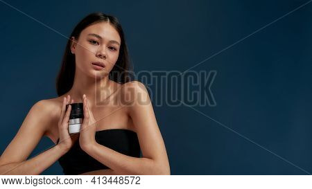 Asian Girl Looking At The Camera While Holding Cosmetics In Her Hands. Youth And Beauty In A Beautif
