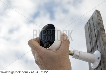 Closeup Of A Male Hand Maintining Surveillance Camera On A Wooden Post, Outdoor Shot