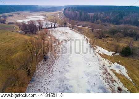 Aerial Evening View At Countryside With Frozen River, Fields And Forest In Early Winter