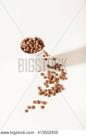 Chocolate In Callets In A White Disposable Cup On A White Background. Home-made Sweets. Top View Clo