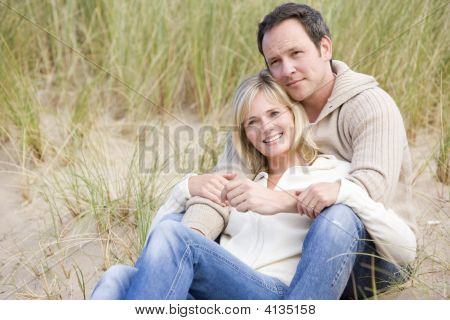 Par sidder på stranden smilende