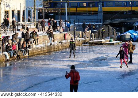 Amersfoort, Netherlands - Feb 13, 2021: Dutch Police Man And Other People Ice Skating On Frozen Cana