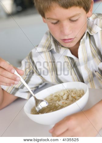 Giovane ragazzo In cucina a mangiare la minestra