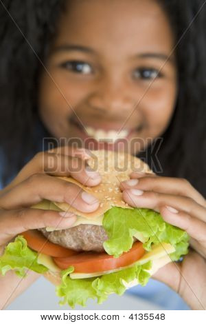 Giovane ragazza mangiare Cheeseburger sorridente
