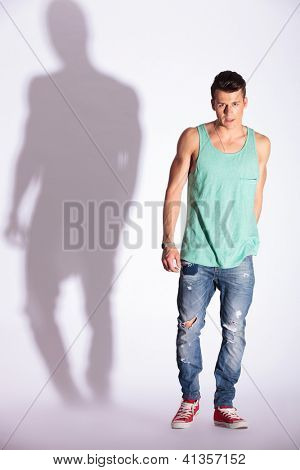 Junge Mode-Mann in die Kamera schaut und auf weißem Hintergrund mit harten Schatten stehend