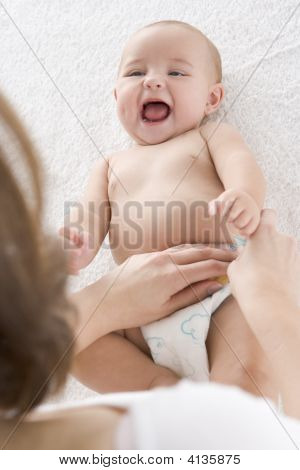 Matka dziecka zmienia pieluchy pomieszczeniu
