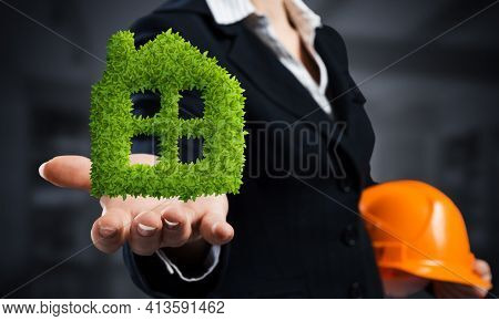 Real Estate Agent Holds In Palm Green Plant In Shape Of House. Woman In Business Suit With Safety He