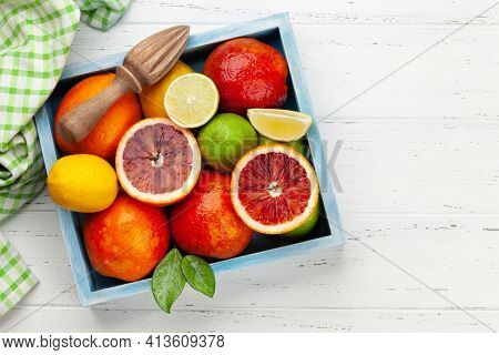 Various fresh citrus fruits in wooden box. Bood orange, lime, lemon. Top view flat lay with copy space