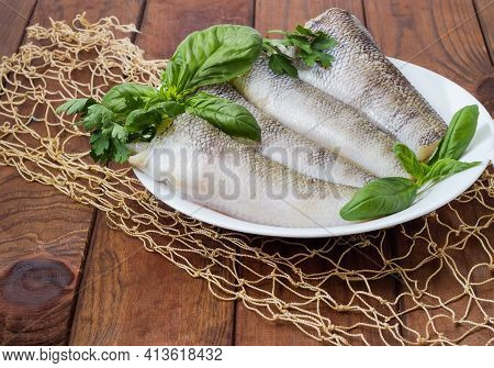 Raw Carcasses Of The Notothenia Fish Without Of Heads And Tails And Twigs Of Greens On Dish On A Rus