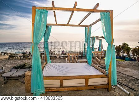 Alanya, Turkey -October 20, 2020: Luxury wood framed whit  curtains for relaxing on the sandy Cleopatra beach in Alanya,  Turkey.