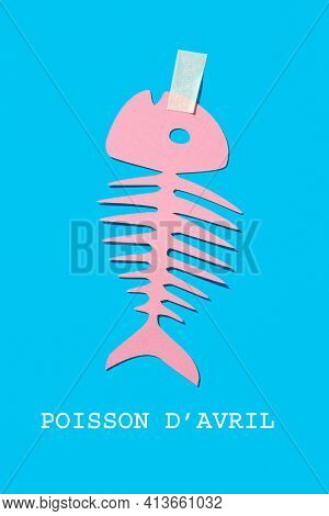 text fish of april written in french, the equivalent of april fools day in france, and a homemade paper fish, as a popular prank in this country, where it is typical to attach it to someones back