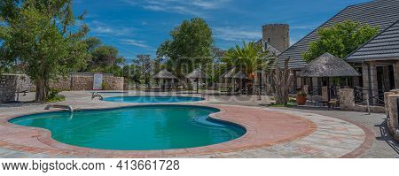 Okaukuejo, Namibia - January 14, 2020 : Okaukuejo Resort With Thatched Roof Houses And Pool In Etosh