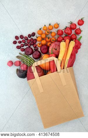 Fresh fruit and vegetables in a paper bag high in lycopene with plant based foods high in anthocyanins antioxidants, fibre, omega 3, vitamins and minerals. Healthy eating concept to lower cholesterol