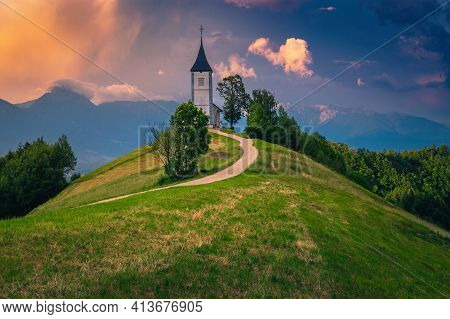Alpine Landscape With Church And Rural Road On The Mountain Ridge. Colorful Sunset Landscape And Cut