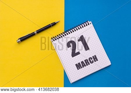 March 21th. Day 21 Of Month, Calendar Date. A Notebook With A Spiral And A Pen Lies On A Yellow-blue