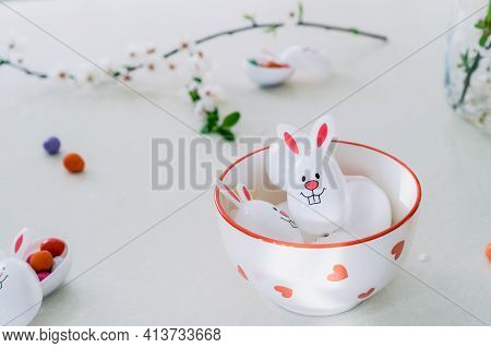 Funny Easter Eggs Containers Filled With Candy And Chocolate Eggs With Bunny Ears In A Bowl On The W