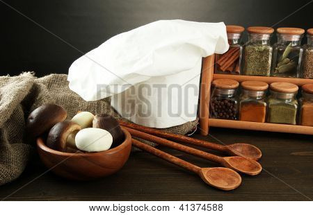 Sammansättning med kockens hatt och kitchenwear på bordet på grå bakgrund