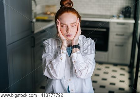 Close-up Portrait Of Tired Redhead Young Woman Massaging Temples, Reducing Painful Head Feelings At 