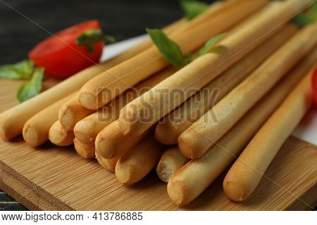 Board With Grissini Breadsticks On Wooden Table, Close Up