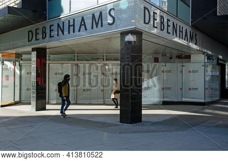 London, Uk - February 26, 2021: Two Pedestrians, Each Wearing Face Masks Walking Past The Closed Doo