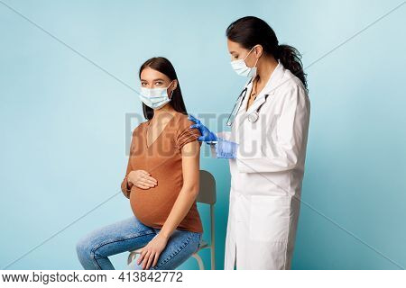 Pregnant Female Patient Getting Vaccinated Covid-19 Vacine Over Blue Background