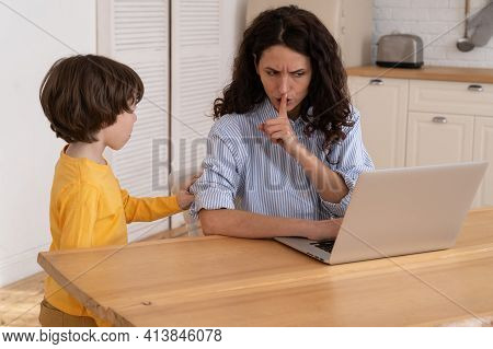 Nervous Mom Sits By The Table At Home Office During Lockdown, Working On Laptop, Asks Not To Make No