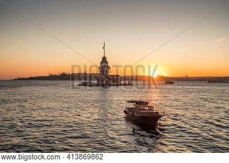 Passenger ferry boat and ?amous Maiden Tower at sunset in Istanbul, Turkey.