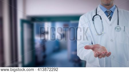 Mid section of male doctor with cupped han standing at hospital. healthcare and professionalism concept standing