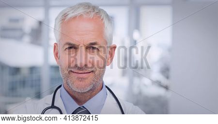Potrait of male caucasian senior doctor wearing lab coat smiling at hospital. healthcare and professionalism concept