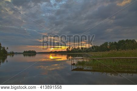 orange sunset in large clowds above river